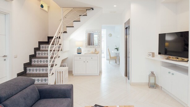 A modern living room with a staircase, a TV, and a dining area. - Villa Totti (Sant'Agnello)