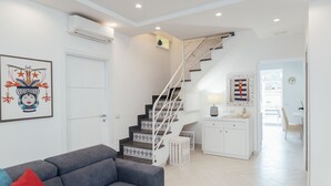 A modern interior with a staircase, white walls, and a grey sofa. - Villa Totti (Sant'Agnello)