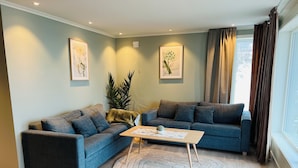 A living room with two sofas, a coffee table, and a large plant. - Olderfjord Turistsenter (Porsanger)