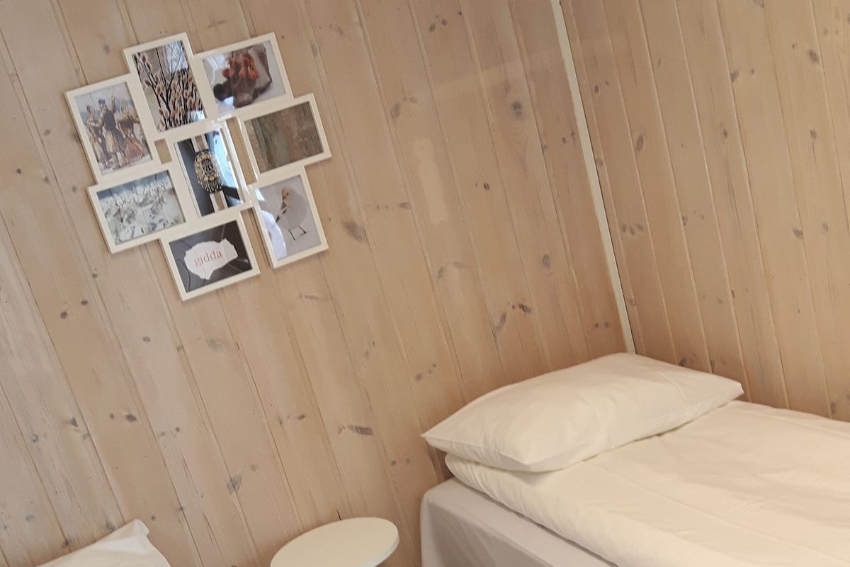 A room with two beds, a small round table, and a wall decorated with framed pictures.