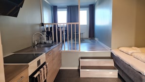 A modern apartment with a kitchenette, a dining area, and a bedroom. - Olderfjord Turistsenter (Porsanger)