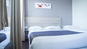 A hotel room with two beds, a wooden headboard, white bedding, and a wall-mounted artwork.