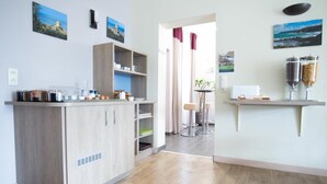 A modern kitchen with wooden cabinets, a built-in coffee machine, and a small dining area with stools.
