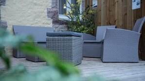An outdoor seating area with wicker furniture, including a sofa and a small table, positioned on a wooden deck.