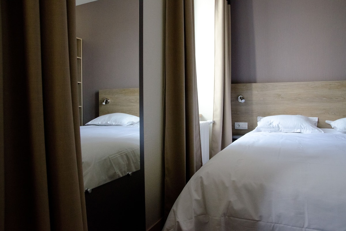 Ein Hotelzimmer mit zwei Betten, einem hölzernen Kopfteil und einem Spiegel, der den Raum widerspiegelt.