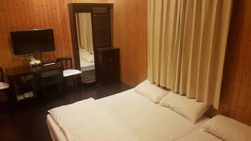 Een hotelkamer met een bed, een bureau met stoel, een televisie en een spiegel.