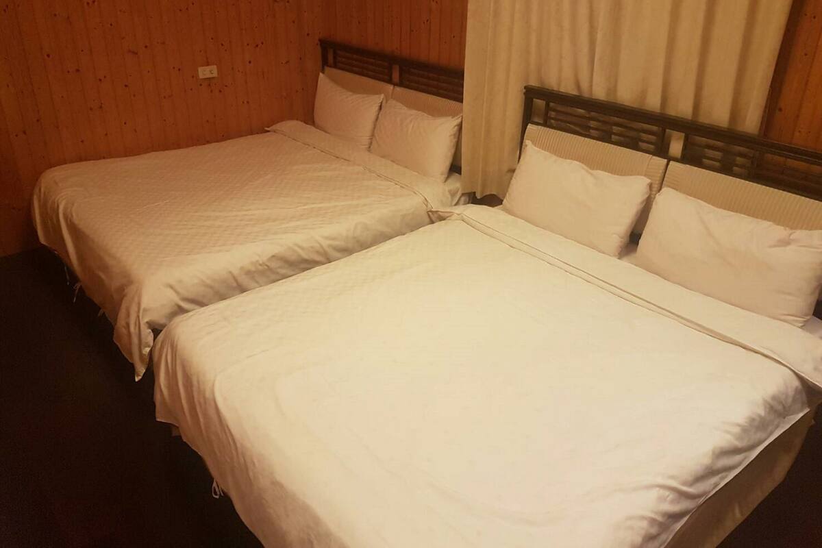 Twee enkele bedden met houten hoofdborden in een kamer met houten wanden.