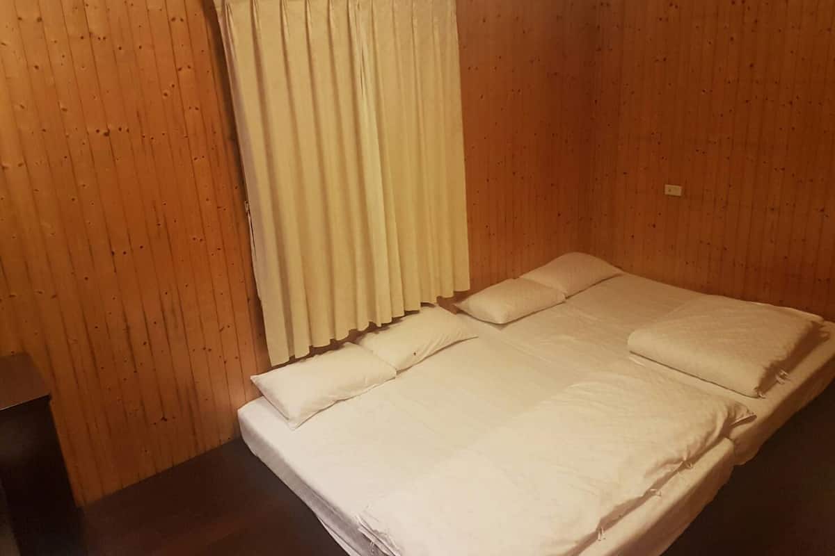 Een eenpersoonsbed met witte beddengoed in een kamer met houten paneelwanden.