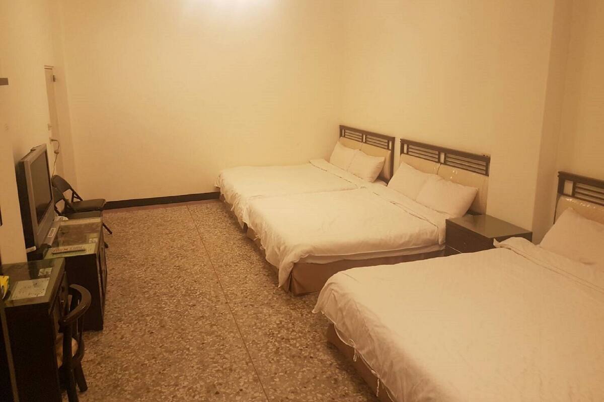 Een hotelkamer met twee eenpersoonsbedden, een bureau met stoel en een televisie.