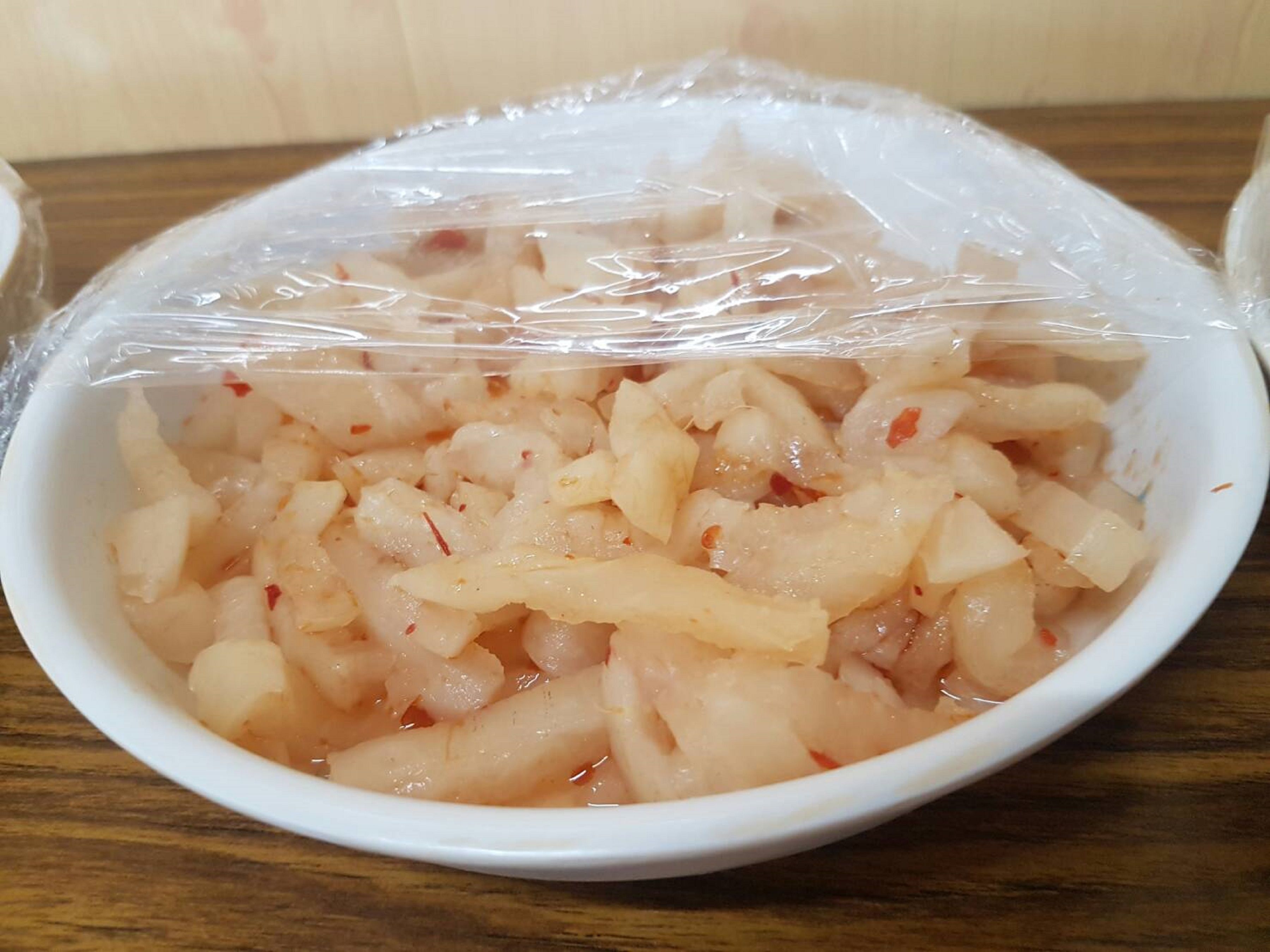 A bowl of food covered with plastic wrap.