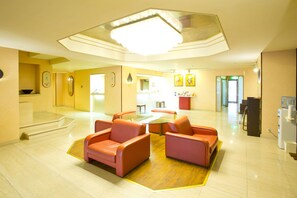 A spacious lobby with a central glass table, orange seating, a large chandelier, and a reception area in the background. - Hotel Ascent Hamamatsu (Hamamatsu)