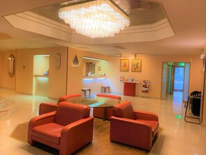 A hotel lobby with a reception desk, a chandelier, red seating, and a clean, modern design. - Hotel Ascent Hamamatsu (Hamamatsu)