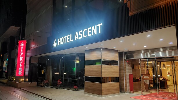 A modern hotel entrance with a prominent 'HOTEL ASCENT' sign, glass doors, and a red carpet leading to the entrance. - Hotel Ascent Hamamatsu (Hamamatsu)