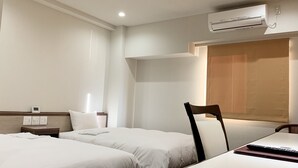 A hotel room with two beds, a desk, an air conditioning unit, and a wall-mounted light fixture. - Hotel Ascent Hamamatsu (Hamamatsu)
