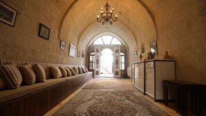 Un couloir avec un long banc, un lustre et un tapis à motifs.