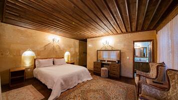 Un dormitorio con una cama grande, techo de madera, dos lámparas de noche, un aparador, un espejo y una alfombra estampada.