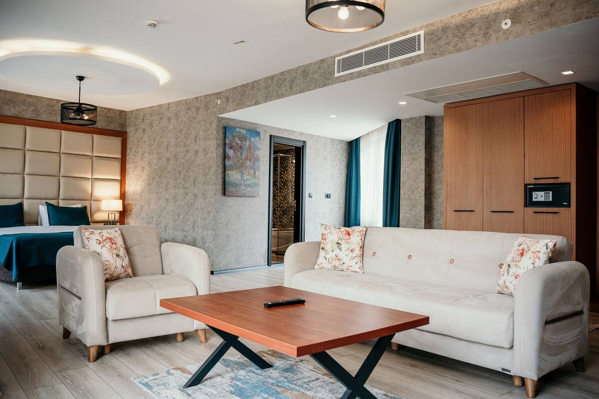 Uma sala de estar moderna com sofá, mesa de centro e uma cama com cabeceira.