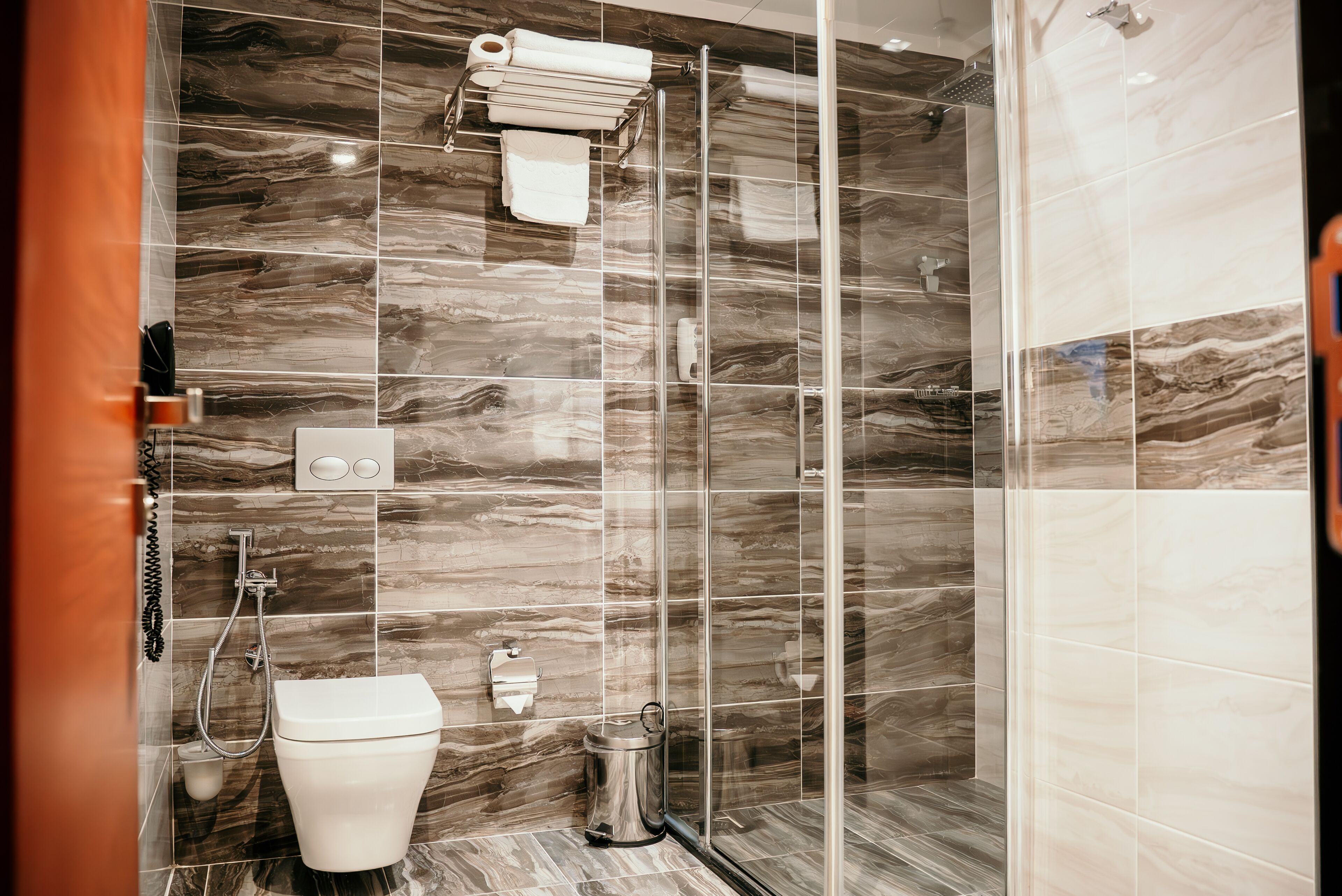 A modern bathroom with a glass shower enclosure, a toilet, and a bidet.