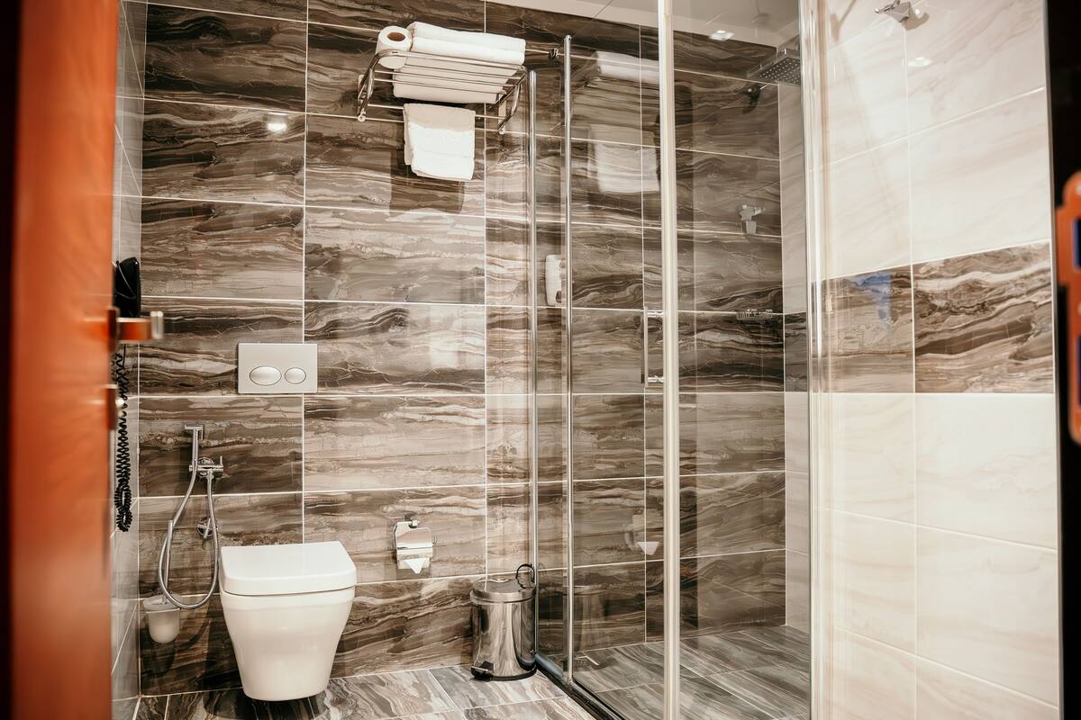 A modern bathroom with a glass shower enclosure, a toilet, and a bidet.