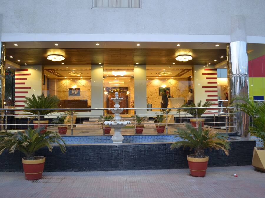 Entrada de hotel con una fuente, plantas en macetas y una zona de recepción.