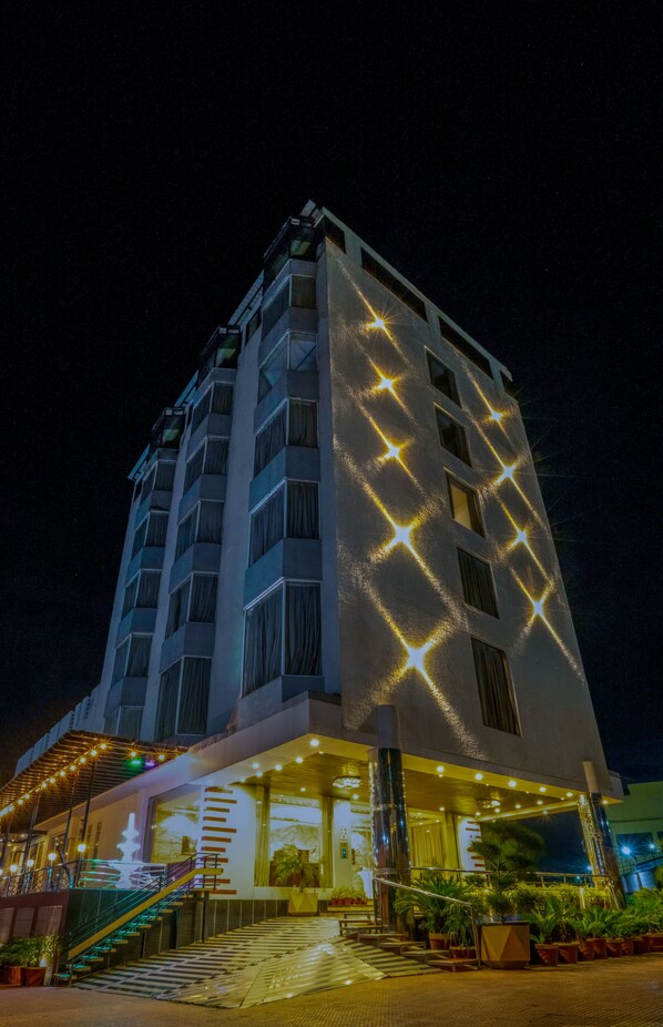 A multi-story hotel with a modern design, featuring a prominent staircase leading to the entrance, and illuminated star patterns on the facade.