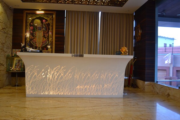Una mesa de recepción con piso de mármol, un letrero de recepción y una estatua decorativa.