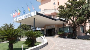 Ein Hotel Eingang mit einem Schild mit der Aufschrift 'HOTEL CAPITAL' und mehreren Flaggen.