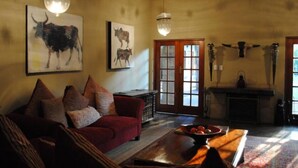 A cozy living room with a red sofa, a wooden coffee table, and artwork of bulls on the walls.