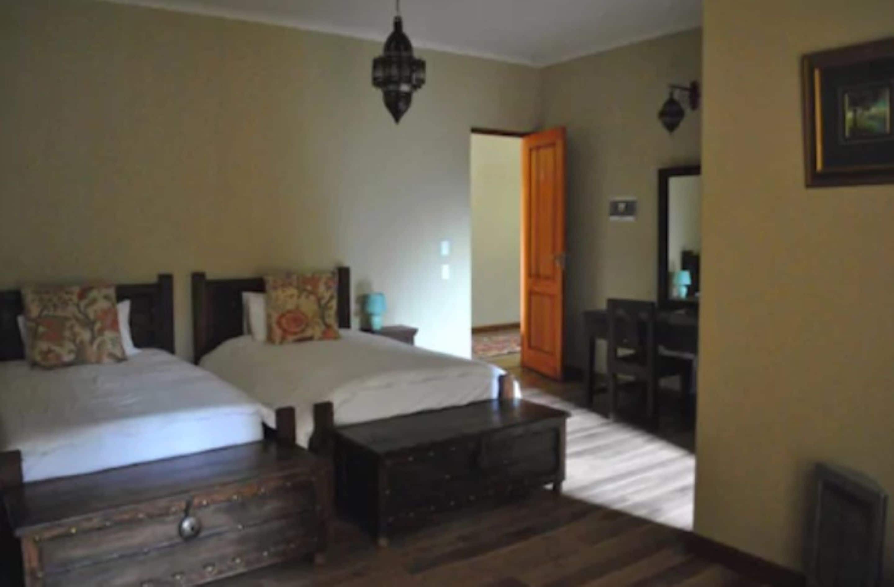 A bedroom with two beds, a wooden dresser, a desk, and a chair.