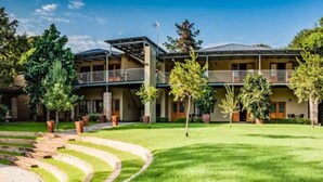 A hotel with a central courtyard, multiple balconies, and a well-maintained lawn.