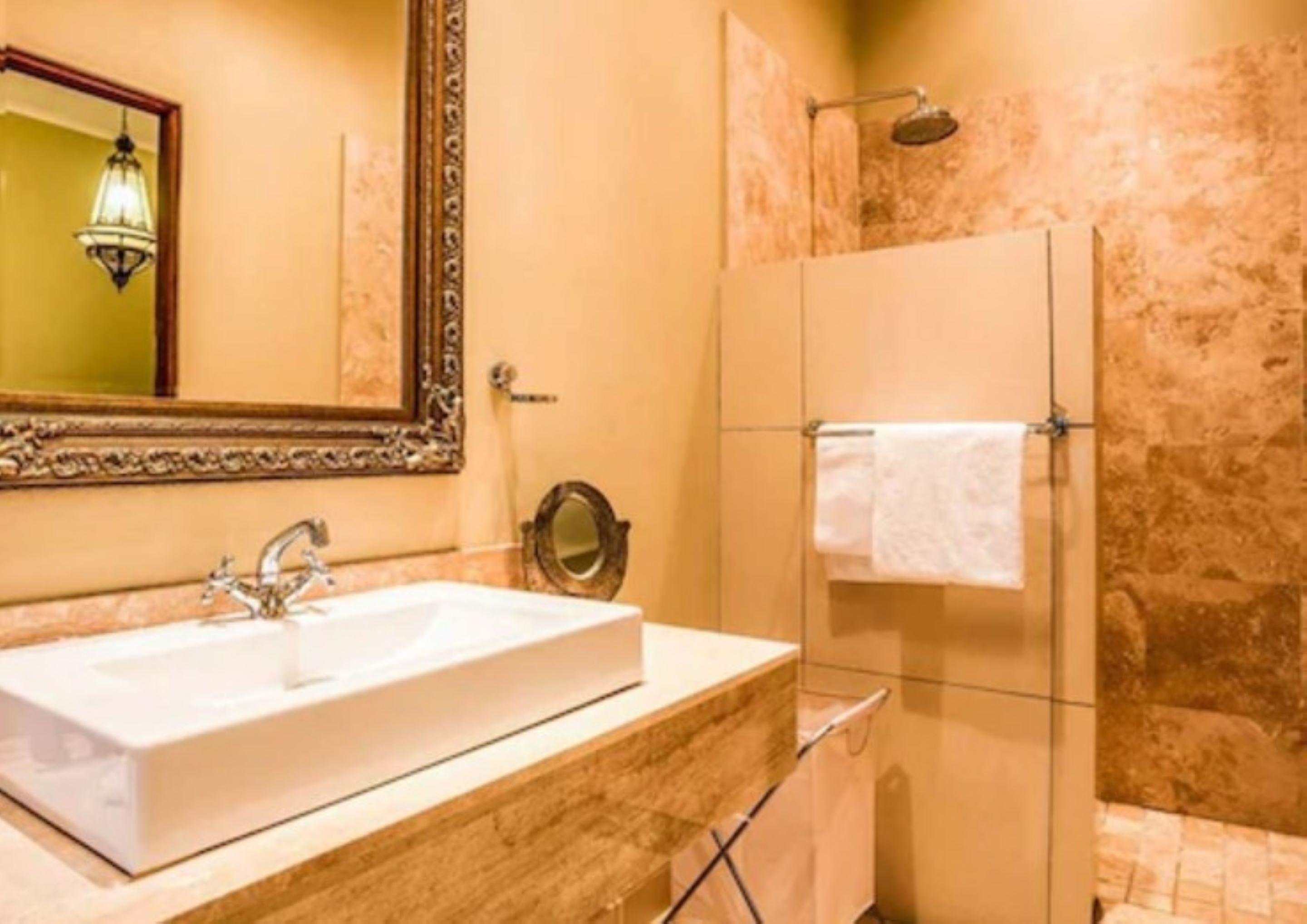 Een badkamer met een groot wastafel, een spiegel, een douche en een handdoekhouder.