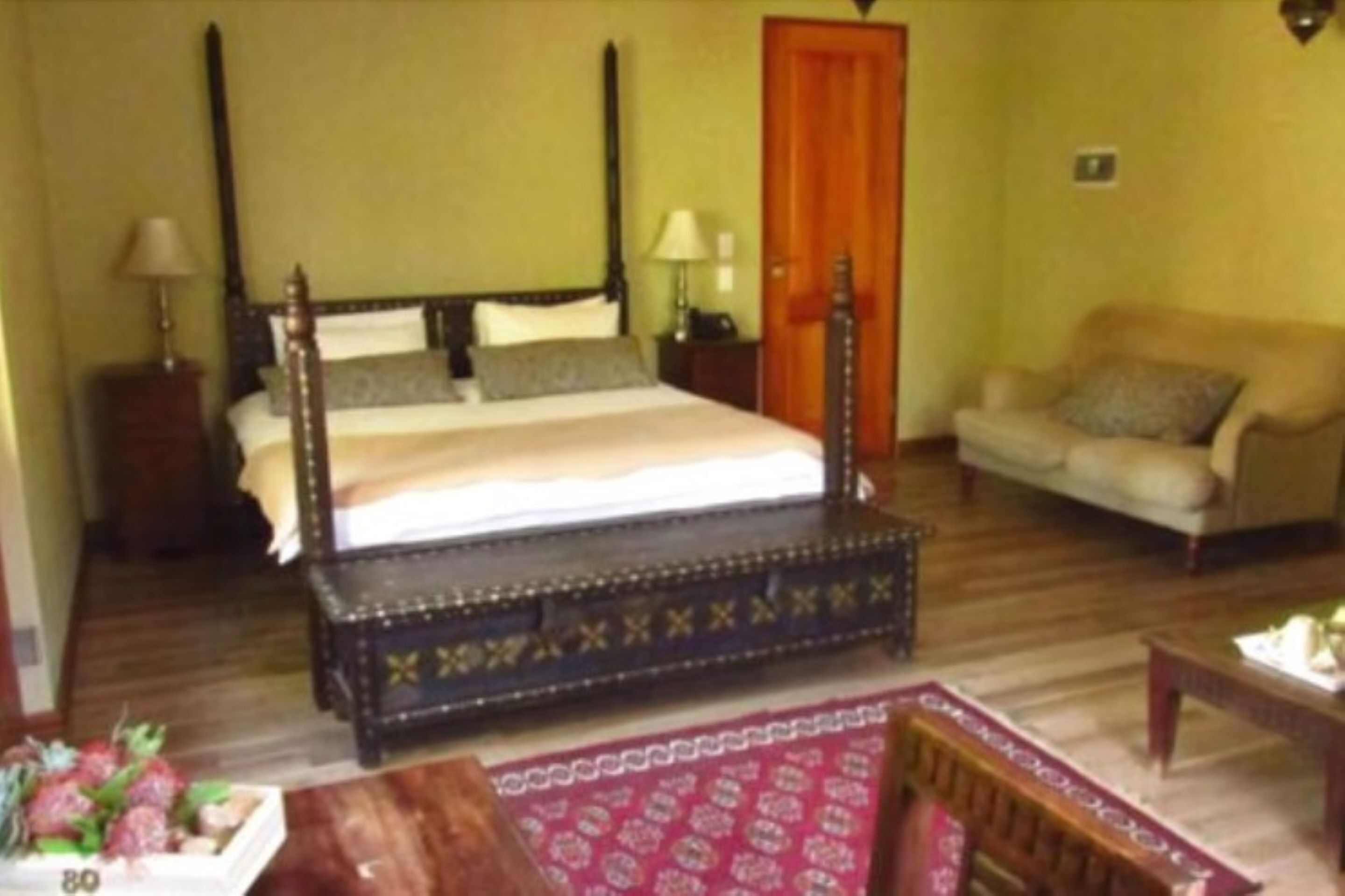 Ein Schlafzimmer mit Himmelbett, einer Couch und Holzboden.