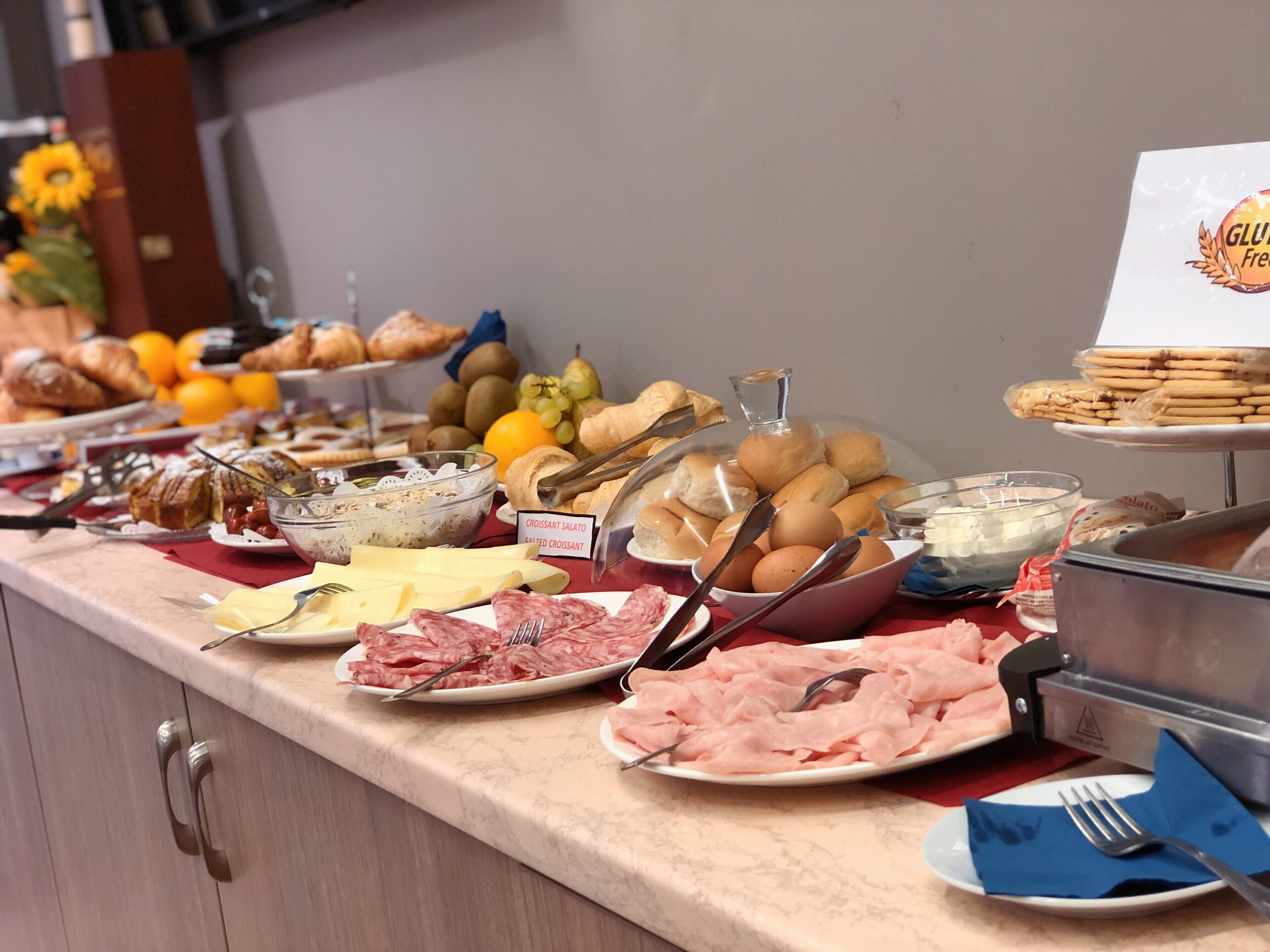 Een buffet met diverse soorten eten, zoals brood, gebak en vlees.