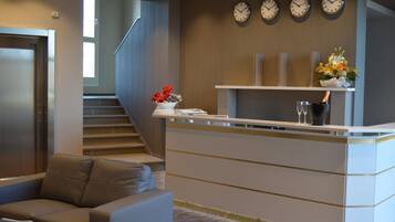 Ein Empfangsbereich mit einer Rezeption, einer Treppe und einer Sitzecke mit einer Couch.