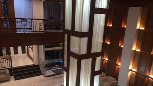 A multi-level hotel lobby with a central column, seating area, and a staircase. - Gold Leaf Hotel (Mandalay)