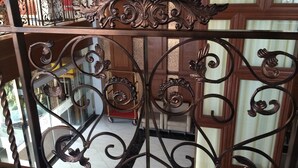 A wrought iron gate with intricate designs, leading to a room with a wooden floor and a view of a street. - Gold Leaf Hotel (Mandalay)