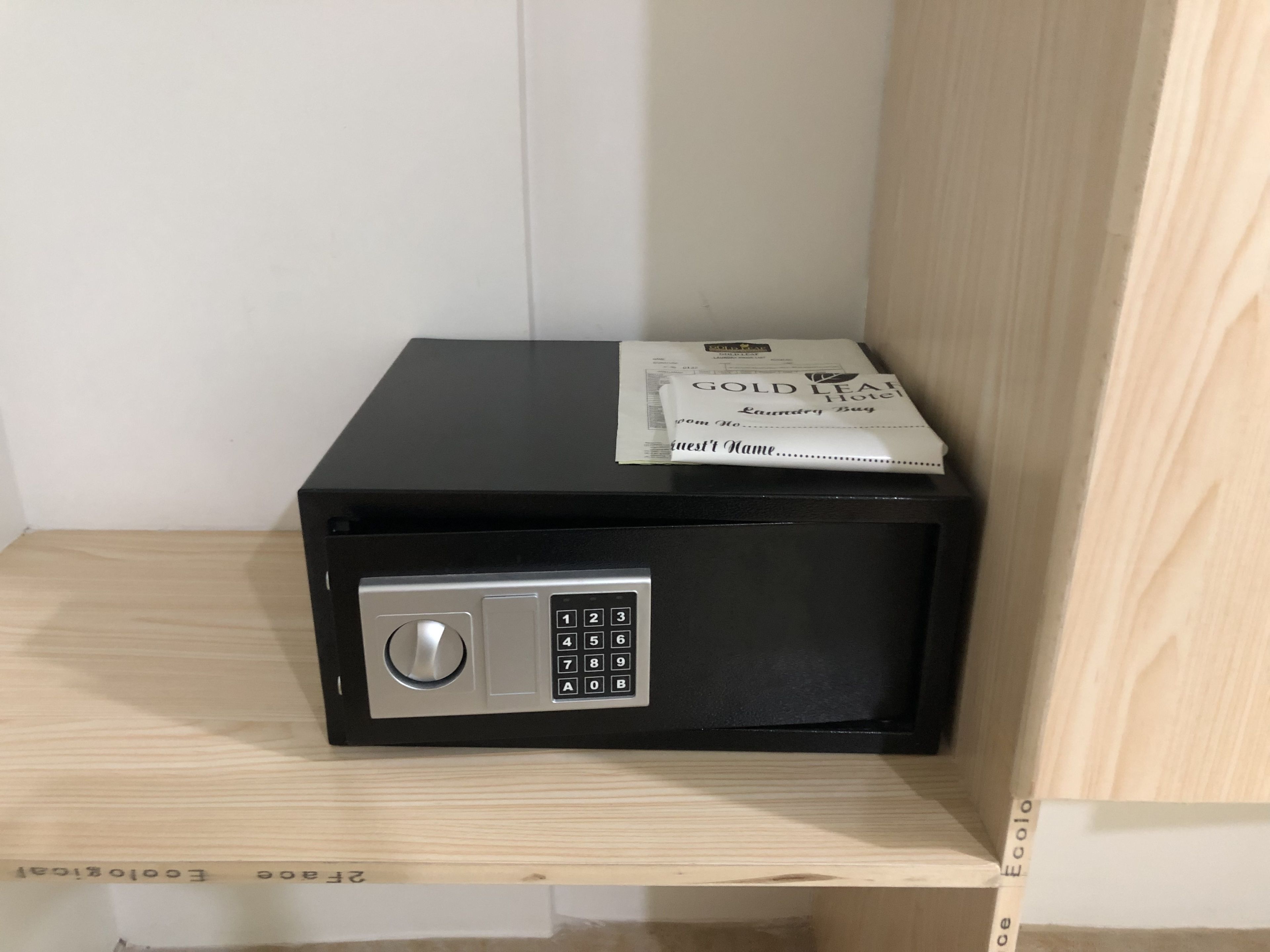 A black safe with a numeric keypad, a hotel receipt, and a note on top.