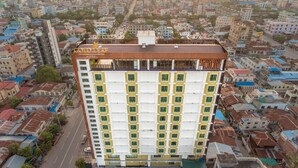 A multi-story hotel with a prominent sign, surrounded by a densely packed urban area with various buildings. - Gold Leaf Hotel (Mandalay)