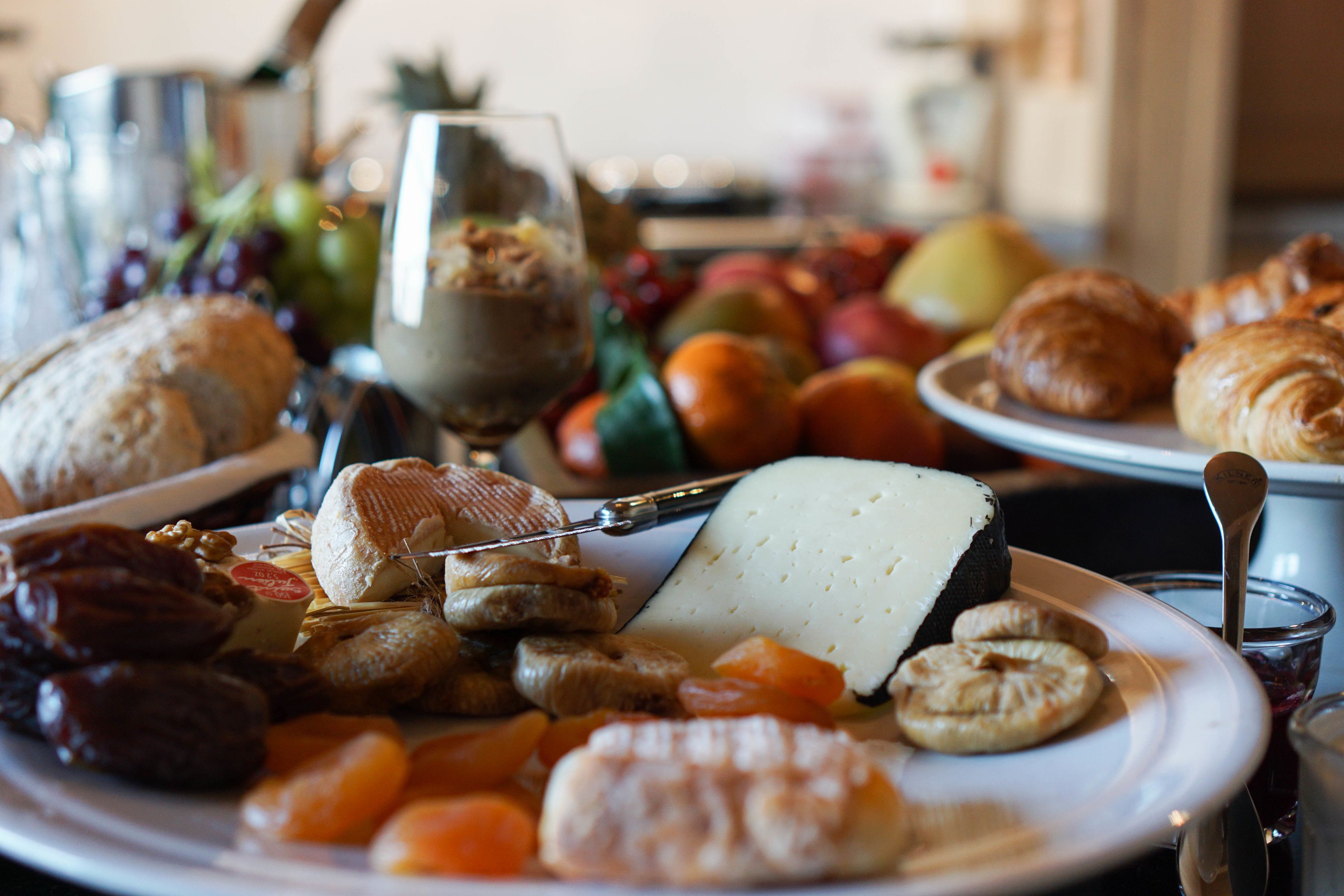 Variedad de alimentos como queso, frutas y pasteles sobre una mesa.