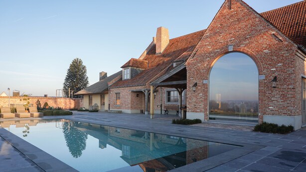 A modern house with a swimming pool, brick exterior, and large archway. - Boutique Hotel De Brakelhoen (Brakel)