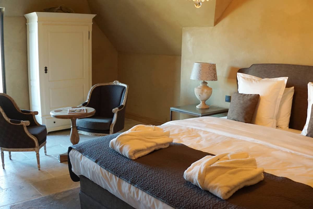 Una habitación de hotel con cama, una silla, una mesa y un armario.