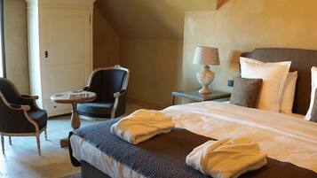 A hotel room with a bed, a chair, a table, and a wardrobe.