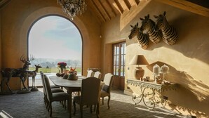 A dining area with a large table, chairs, a chandelier, and wall-mounted zebra sculptures. - Boutique Hotel De Brakelhoen (Brakel)