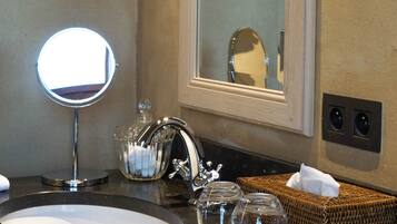 A bathroom with a round mirror, a sink, and a large mirror above it.