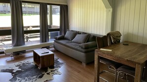 A modern living room with a sofa, a wooden coffee table, and a dining table with chairs. - Chiemgautraum (Siegsdorf)