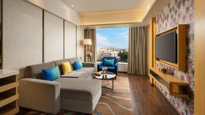 A modern hotel room with a sofa, armchair, and a flat-screen TV. - Wow Crest, Indore – IHCL SeleQtions (Indore)