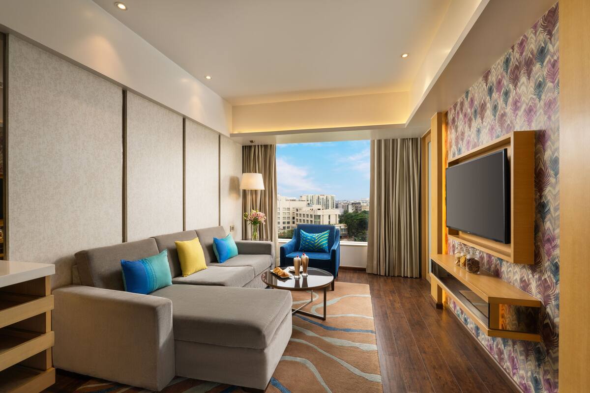 Una habitación de hotel moderna con sofá, sillón y televisor de pantalla plana.