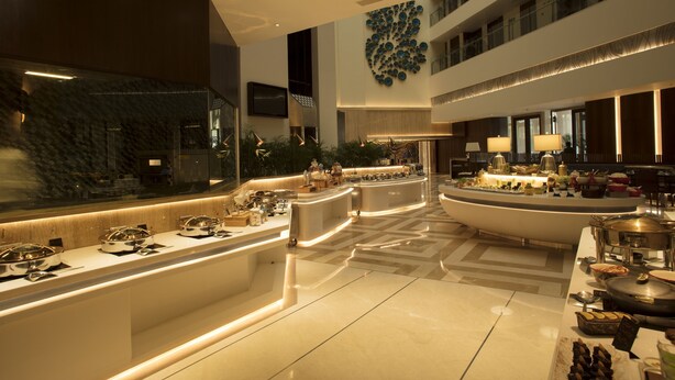A modern hotel lobby with a central island counter, multiple seating areas, and a large decorative wall. - Wow Crest, Indore – IHCL SeleQtions (Indore)