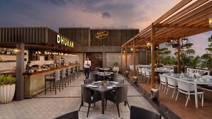 A restaurant with outdoor seating, a bar area, and a sign reading "DHUMAN". - Wow Crest, Indore – IHCL SeleQtions (Indore)