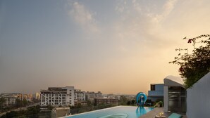 A rooftop infinity pool with a view of the cityscape, a modern lounge area, and a unique blue water feature. - Wow Crest, Indore – IHCL SeleQtions (Indore)